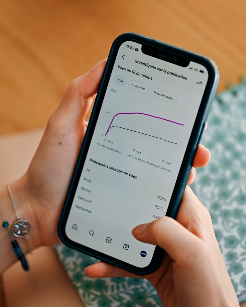 Hands holding a phone displaying social media performance statistics
